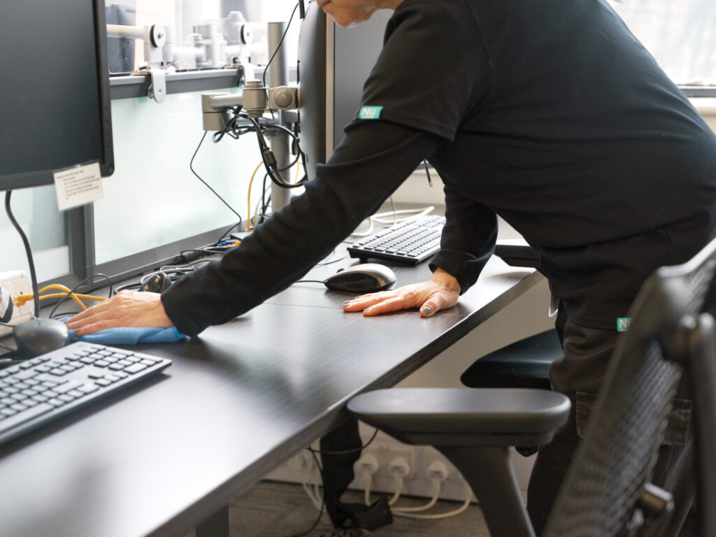 A NuServe operative cleaning a desk.