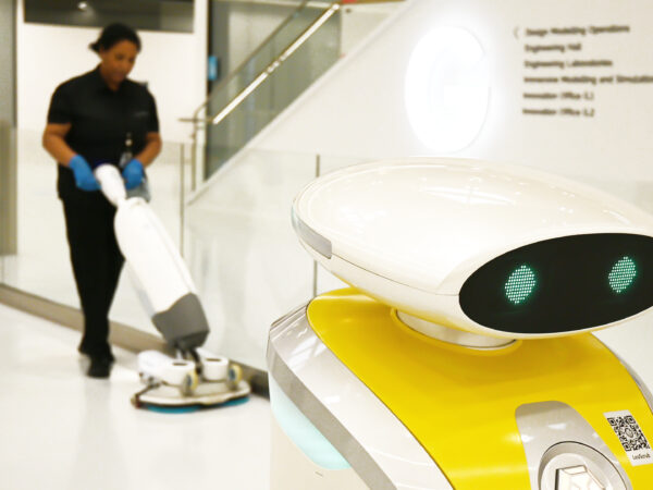 robot cleaning with a cleaner in the background