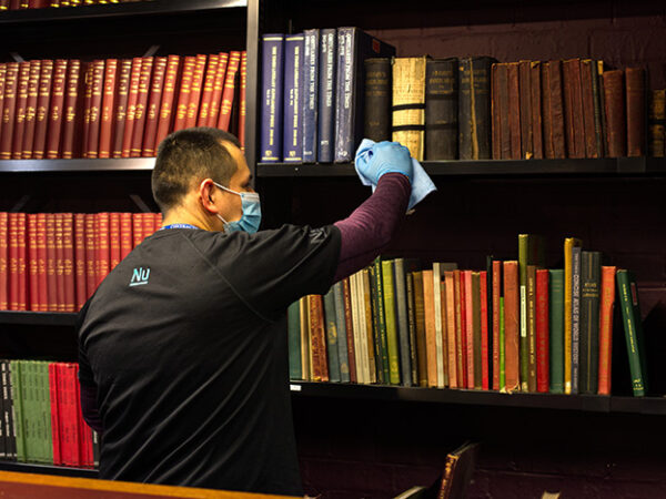 Cleaner wiping bookshelves in the London Library