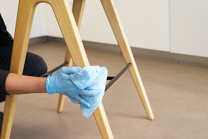 A NuServe operative wiping a chair.