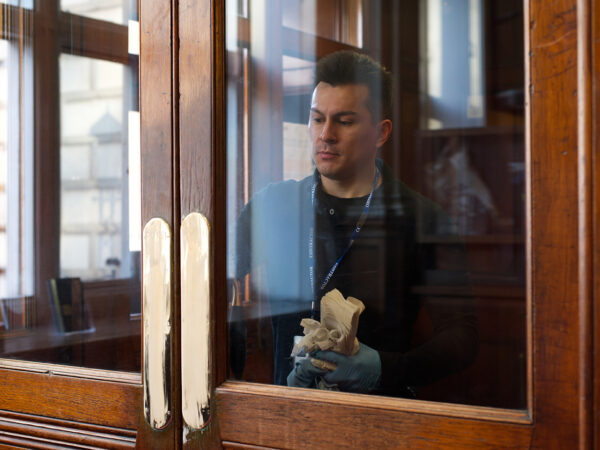 A NuServe operative wiping down a door window.