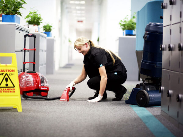 A NuServe operative cleaning an office carpet.