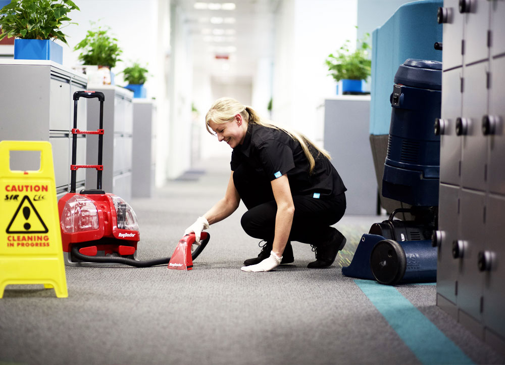 A NuServe operative cleaning an office carpet.