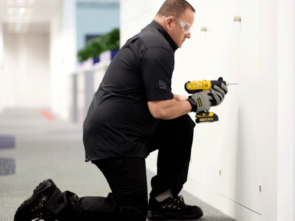 A maintenance worker drilling a wall.