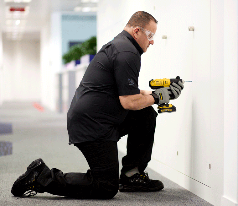 A maintenance worker drilling a wall.