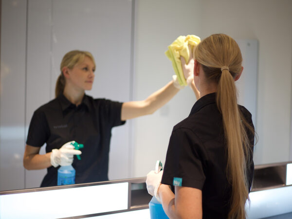 A NuServe operative cleaning a bathroom.