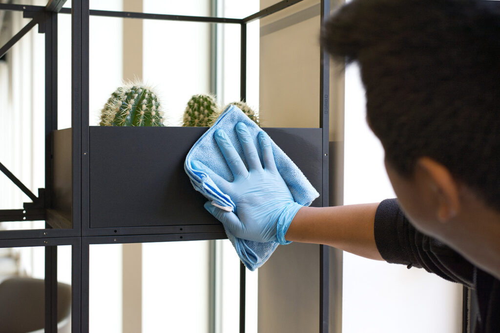 A NuServe cleaner wiping down a plant installment.