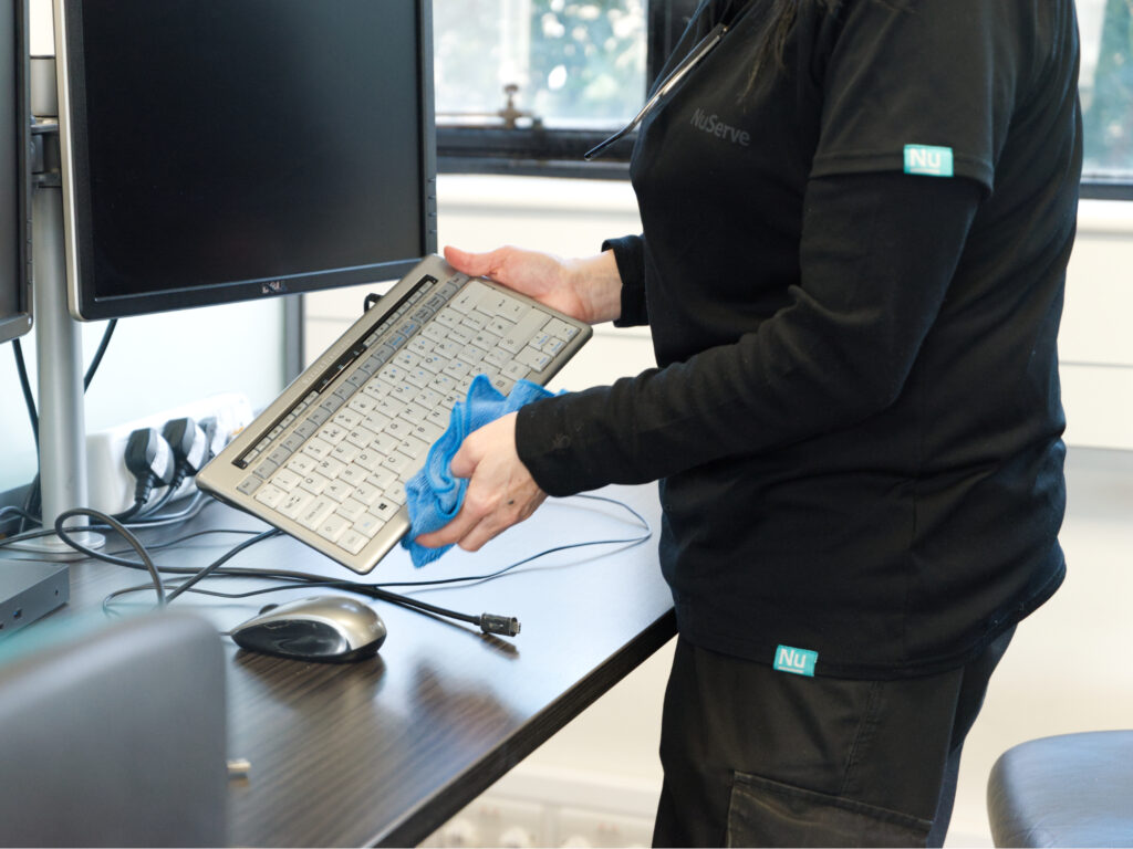A NuServe cleaner sanitising a computer keyboard.