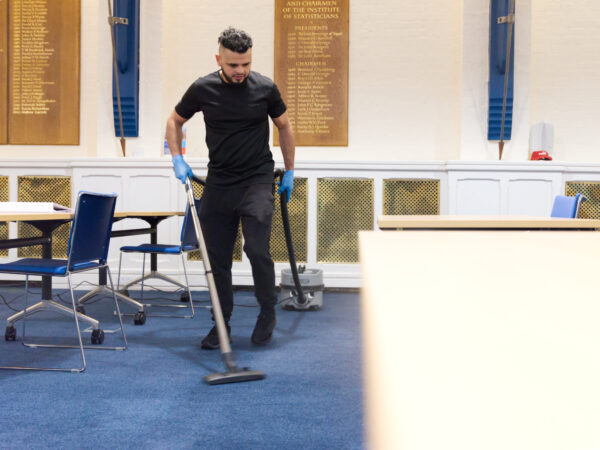 A NuServe cleaner vacuuming carpet.