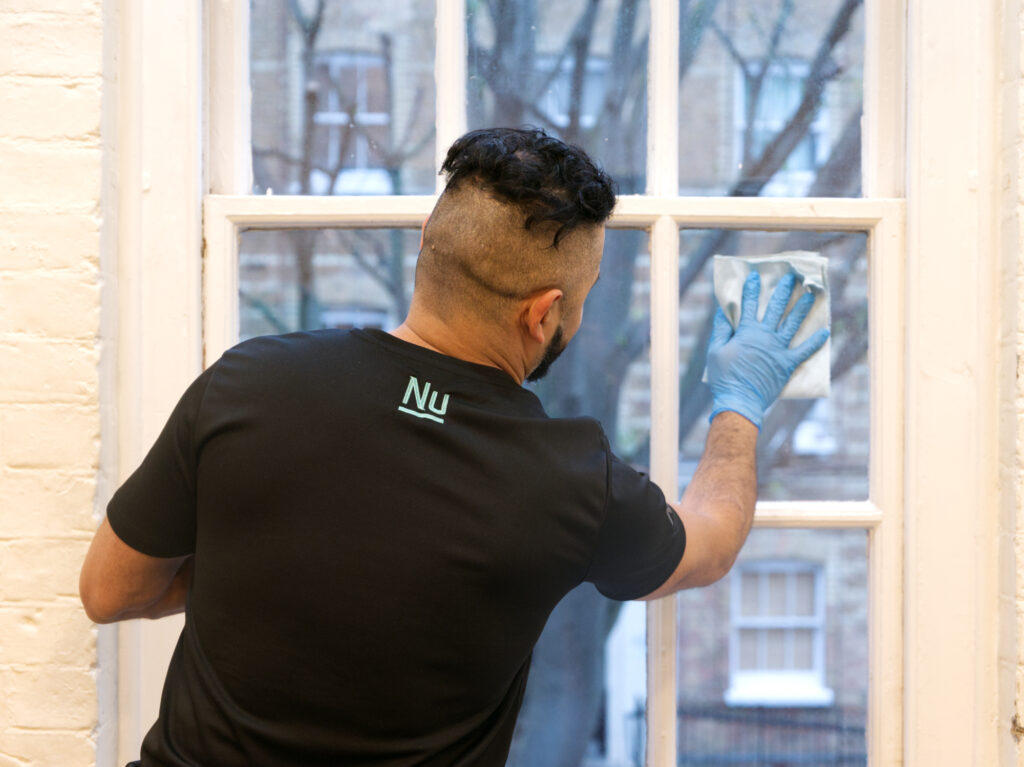 A NuServe cleaner wiping a window.