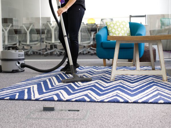 A NuServe cleaner vacuuming a carpet.